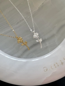 Detail shot of 3D rose flower pendants in gold and silver finish with fine link chains