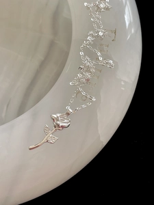 Detailed close-up of a silver rose flower pendant necklace with fine petal textures