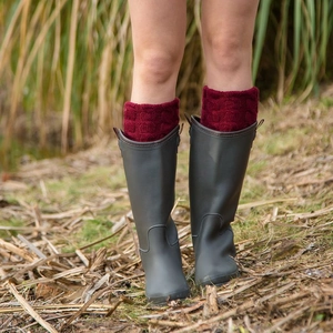 Deep olive rain boots with burgundy cable knit leg warmers on outdoor grass