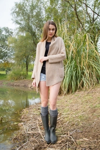 Outdoor view of gray cable knit leg warmers paired with dark green tall rain boots