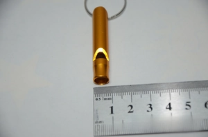 Close-up of golden aluminum survival whistle with measuring ruler showing 4.5cm length