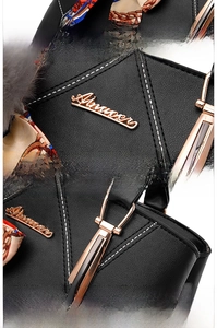 Close-up of black litchi pattern leather bag with gold logo and plush ball accessory