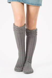 Close-up of gray chunky knit leg warmers showing intricate cable stitch texture