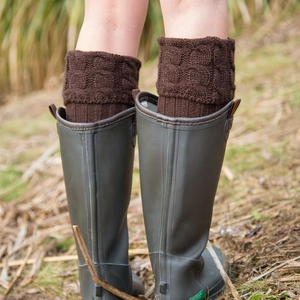 Deep brown cable knit boot cuffs paired with grey rain boots on grass