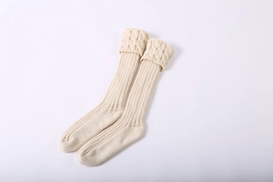 Detail view of cream cable-knit leg warmers showing intricate braided texture and ribbed cuff