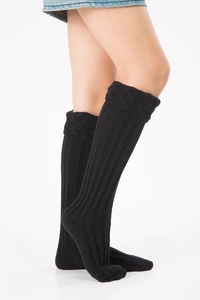 Close-up of black cable knit leg warmers with thick twist texture and ribbed cuffs
