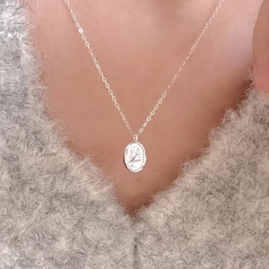 Minimalist 925 sterling silver necklace with oval plant relief pendant on grey sweater