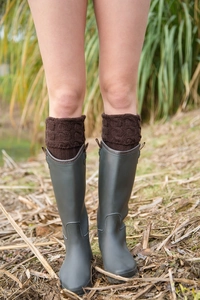 Detailed knit texture of coffee brown boot cuffs paired with stylish rain boots on grass