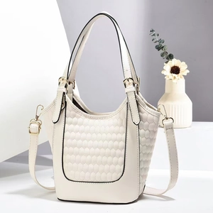 Sac seau matelassé beige minimaliste avec détails dorés dans un cadre élégant