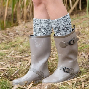 Glossy light gray rain boots with knitted socks and adjustable buckle on outdoor grass