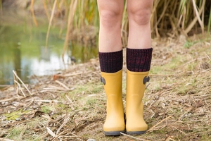 Detail of yellow rain boots with thick knit lining and side buckle in an outdoor setting