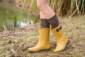 Outdoor shot of mustard yellow mid-calf rain boots with decorative side buckles