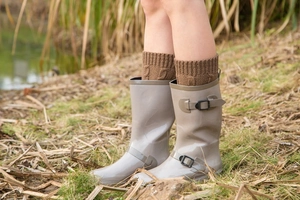 Close-up of waterproof rain boots with knit leg warmers and buckle detail in outdoor setting