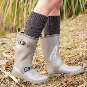 Knit cable leg warmers styled with rain boots on grass for cozy winter outdoor wear