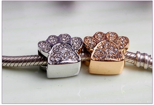 Close-up of gold and silver paw print beads with crystals on a snake chain bracelet