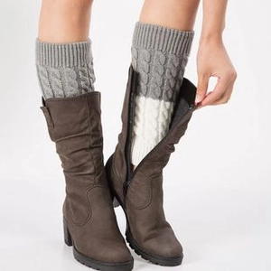 Detail of cable knit leg warmers in grey and white color block styled with boots
