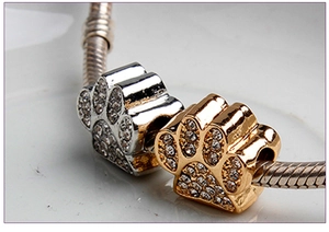Macro shot of silver and gold paw-shaped charms with sparkling rhinestones for jewelry
