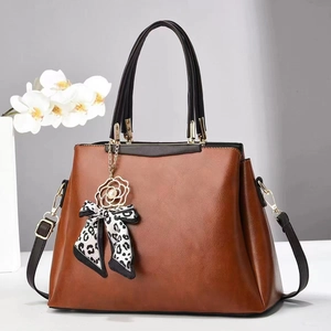 Brown PU leather tote bag with black handles and floral pendant accessory