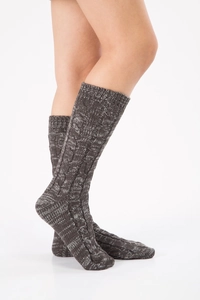 Close-up of dark grey cable knit wool socks with ribbed cuffs on model's feet