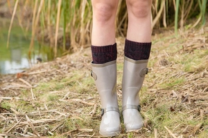Detail of light grey glossy rain boots with thick burgundy and black knit boot liners