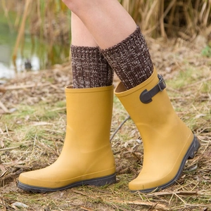 Yellow mid-calf rain boots with brown knit socks shown in an outdoor grass setting