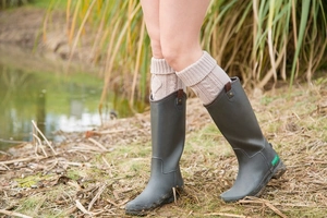 Detailed knit texture of beige cable knit leg warmers worn over dark grey boots
