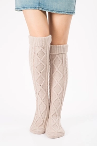 Detail of beige cable-knit over-knee leg warmers with diamond pattern on knit fabric