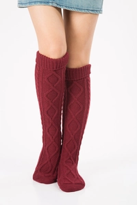 Macro detail of wine red knee-high knitted leg warmers with diamond pattern texture