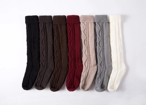 Detailed knit texture display of various colored cable-knit over-knee leg warmers