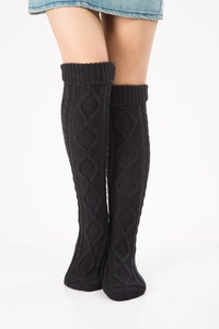 Detail of black cable-knit over-the-knee leg warmers with diamond pattern texture
