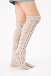 Detail view of beige cable knit over-the-knee socks showing texture and long length