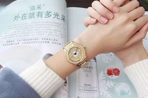 Close-up of luxury gold ladies watch with crystal encrusted dial and metal chain strap
