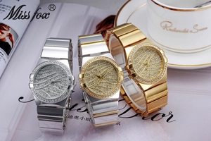 Three luxury diamond-encrusted quartz watches in gold and silver on a fashion magazine