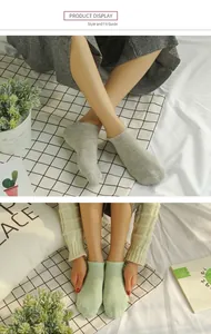 Detail view of low-cut cotton ankle socks in grey and pale green on model feet