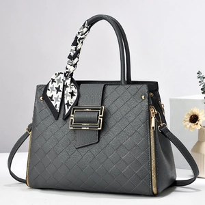Détail du sac à main gris foncé avec texture tissée, boucle dorée et foulard pied-de-poule