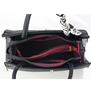Détail de l'intérieur d'un sac noir montrant les compartiments bordeaux et le zip doré