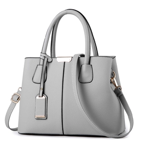 Minimalist grey lychee leather handbag with gold hardware and adjustable strap on white background