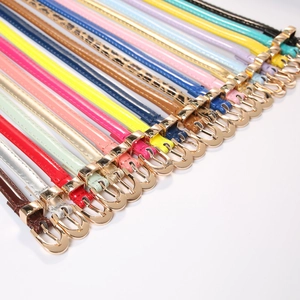 Multiple colorful skinny waist belts for women with gold buckles on white background