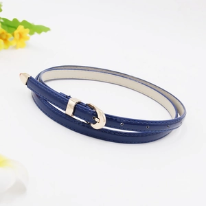 Detailed macro view of a thin blue patent leather belt with a sleek gold metal buckle
