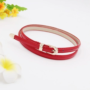 Detail of red patent leather skinny belt with gold metal buckle and white stitching