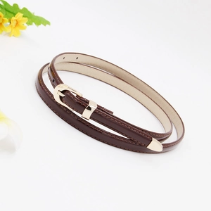 Detail of slim dark brown leather belt with gold metal buckle and tip on white background