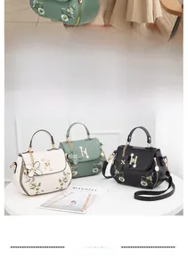 Close-up of floral embroidery and pearl H-buckle detail on the crossbody bag