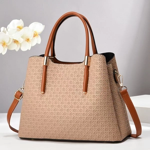 Detail of beige woven tote bag with brown leather handles and golden metal hardware