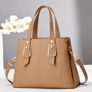 Detail of tan lychee grain leather handbag with gold metal buckles and white orchids
