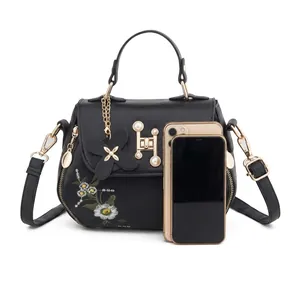 Detailed size comparison of black crossbody bag with daisy embroidery and gold hardware
