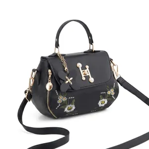 Detail shot of elegant daisy embroidery and H-shaped metal buckle on the black PU handbag
