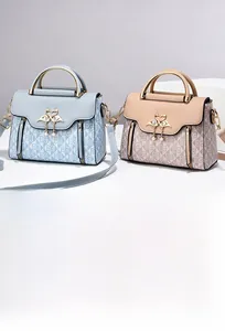 Dettaglio borsa in pelle monogram con chiusura a cigno, pendente di perla e manico in metallo