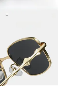Detail of square sunglasses with gold metal frame and dark gray lenses featuring nose pads