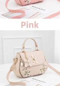Detail of pink crossbody bag featuring delicate daisy embroidery and butterfly charm