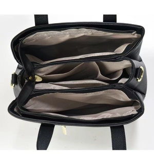 Internal view of black leather tote bag with multiple compartments and golden zippers